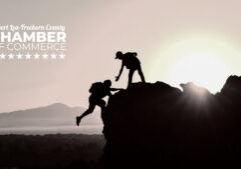 a person gives a hand to another climbing a mountain. The Albert Lea-Freeborn County Chamber logo is in the top left corner